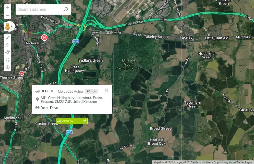 A vehicle pop-up on the Fleetalyse live map: registration, model, speed, address and driver of a Mercedes Actros on the M11, with a second vehicle on the road below it.